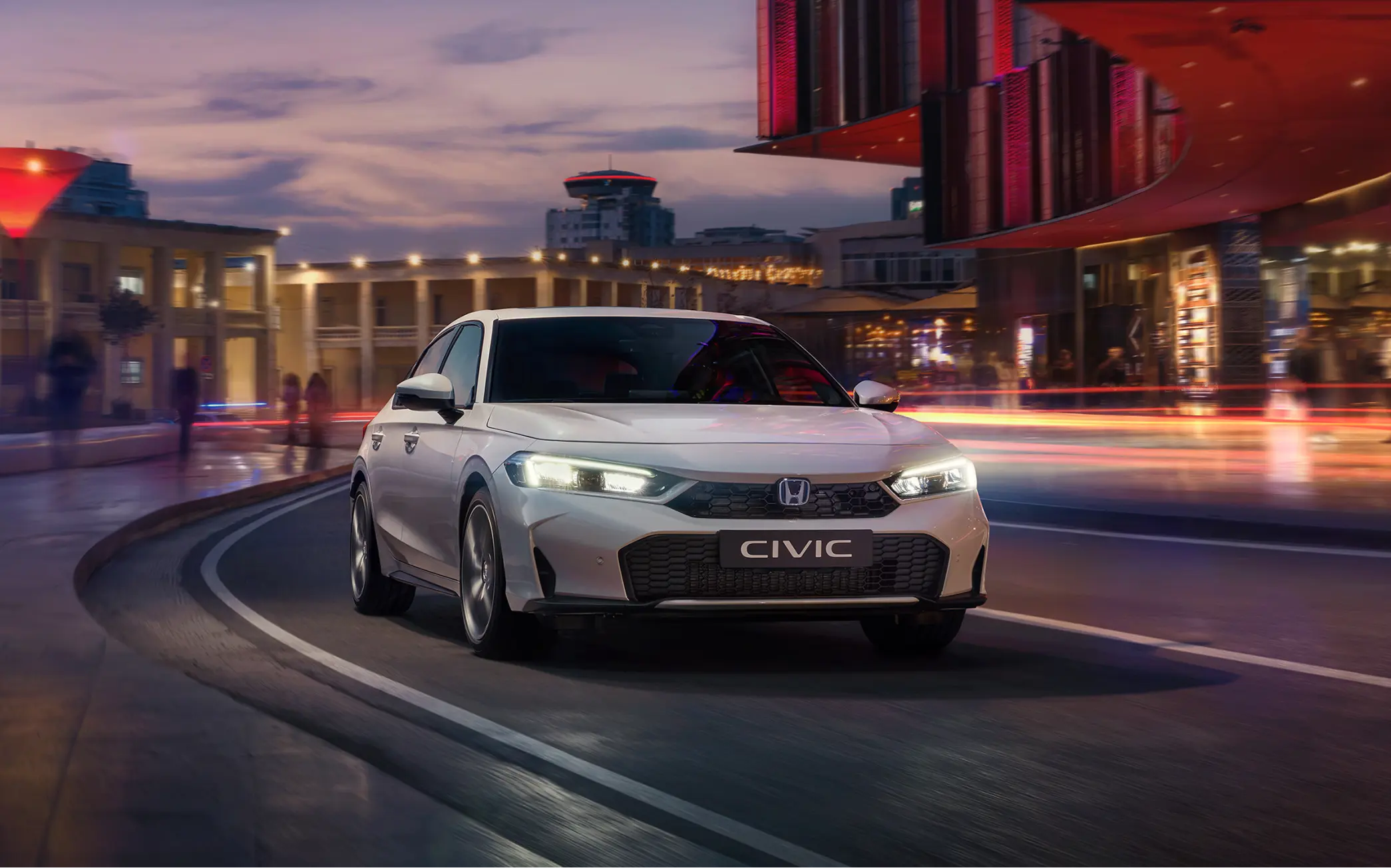 Honda Civic Hybrid pri jazde mestom za úsvitu.