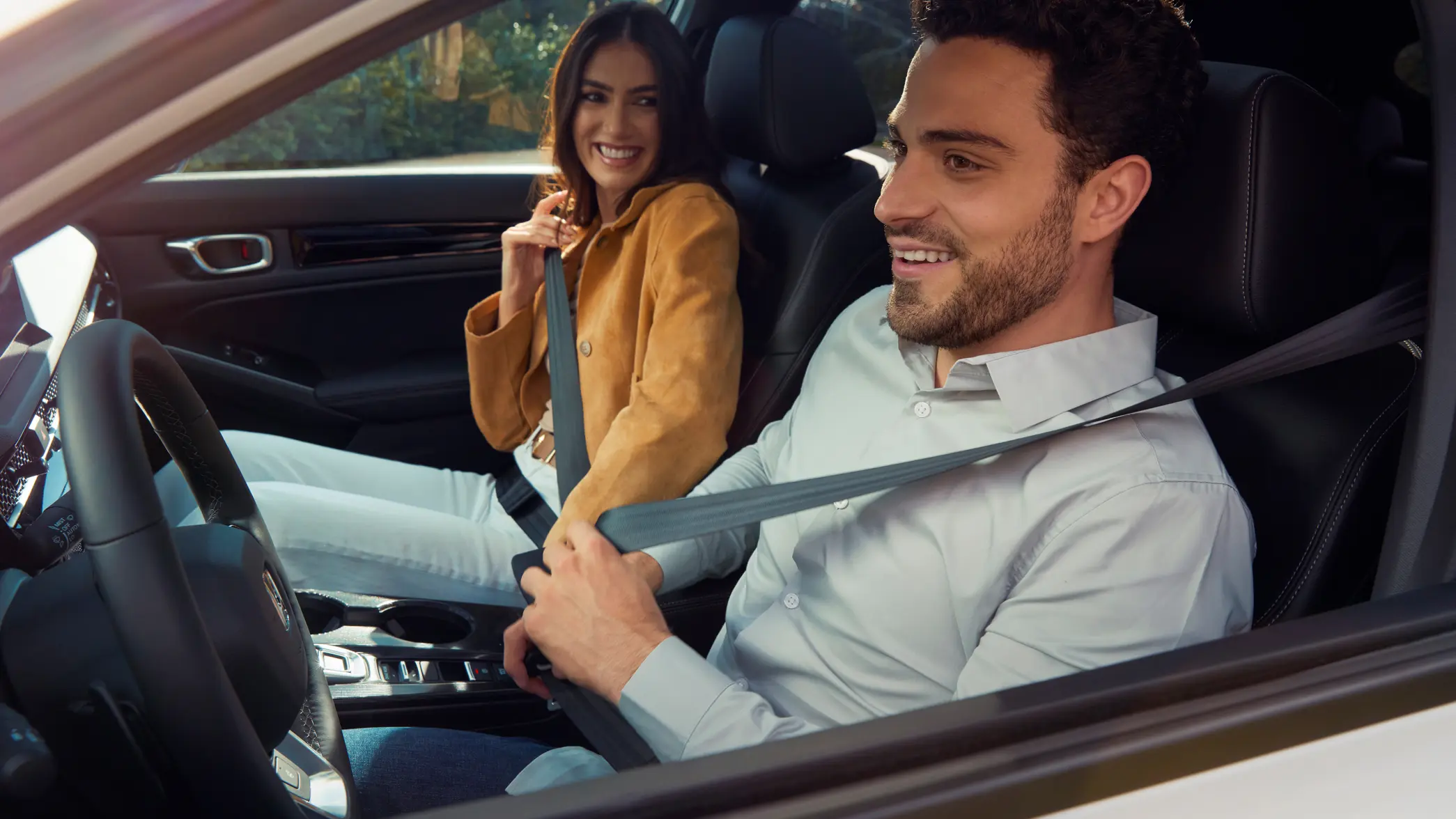 Dvaja ľudia si zapínajú bezpečnostné pásy vo vnútri vozidla Honda Civic Hybrid.